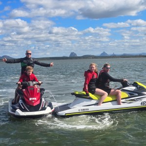 Three people on jet skis in open water under a cloudy sky.