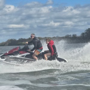 Two people riding a jet ski on a lake with splashing water.