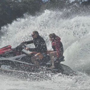 Two people riding a jet ski with water splashing around them.